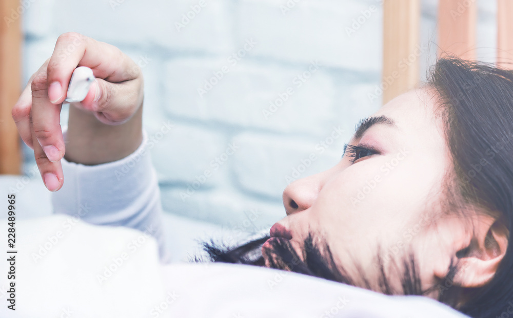 Asian woman use a thermometer to detect fever in bedroom.color tone Asian woman use a thermometer to detect fever in bedroom.color tone