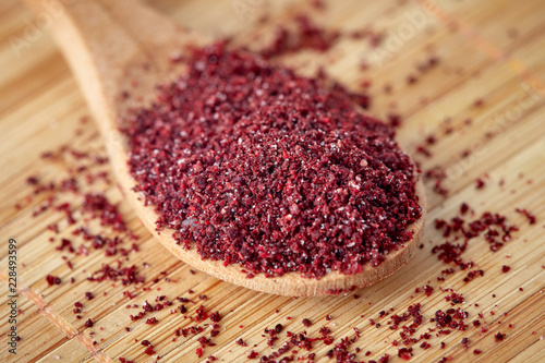 Fototapeta Naklejka Na Ścianę i Meble -  Close up of ground sumac spice powder in wooden spoon