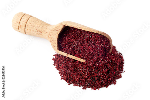 Fotografía Ground sumac spice powder in wooden scoop isolated on white background