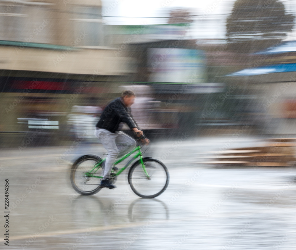 Fototapeta premium Cyclist on the city roadway on a rainy day in motion blur