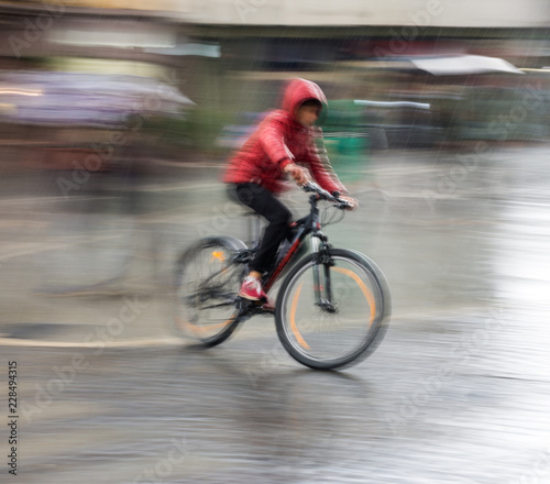 Fototapeta Naklejka Na Ścianę i Meble -  Cyclist on the city roadway on a rainy day in motion blur