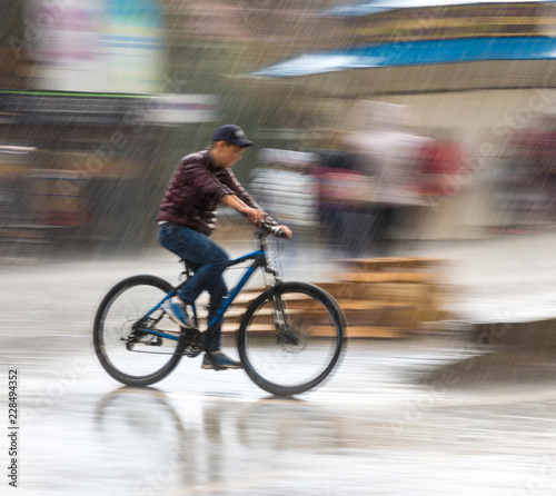 Cyclist on the city roadway on a rainy day in motion blur © vbaleha