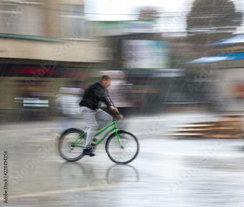 Cyclist on the city roadway on a rainy day in motion blur