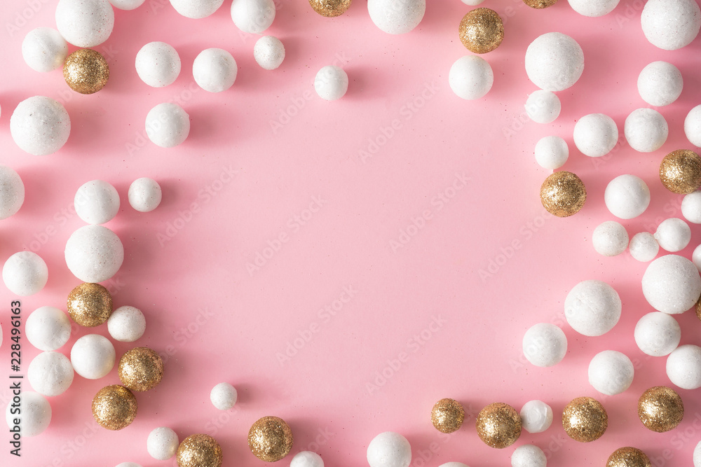Christmas pink background with copy space made of gold and white glitter ball decoration. New Year party greeting card minimal style. Flat lay