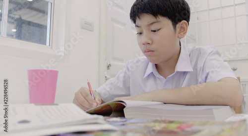 Asian child in student uniform to do homework at home.