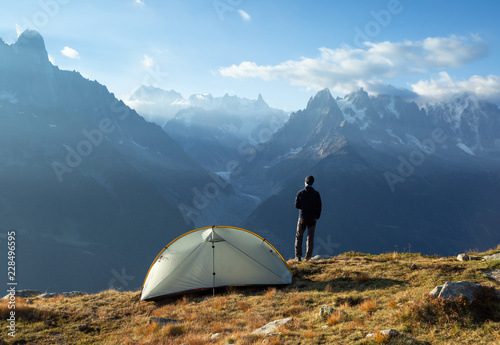 A hiker enjoying the awesome view and a cup of coffee at his campsite in the mountains. photo