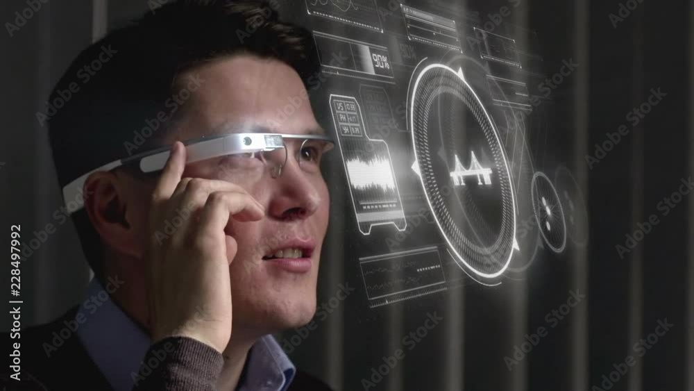 Close up of cheerful Asian man using the touch pad built on the side of smart glasses and looking at virtual interface projected in the air
