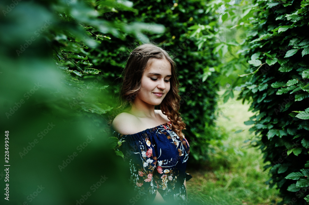 Portrait of a fabulous young girl in pretty dress with stylish curly hairstyle posing in the forest or park. Portrait of a fabulous young girl in pretty dress with stylish curly hairstyle posing in the forest or park.