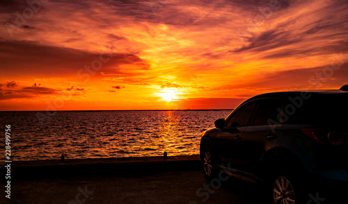 Blue compact SUV car with sport and luxury design parked on concrete road by the sea at sunset. Electric car technology and business. Hybrid auto and automotive. Tropical road trip travel. Automotive