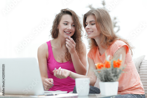 two young women discuss the video with laptop sitting at a coffee table