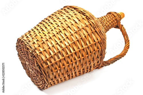 Old demijohn wicker wrapped glass bottle isolated on white