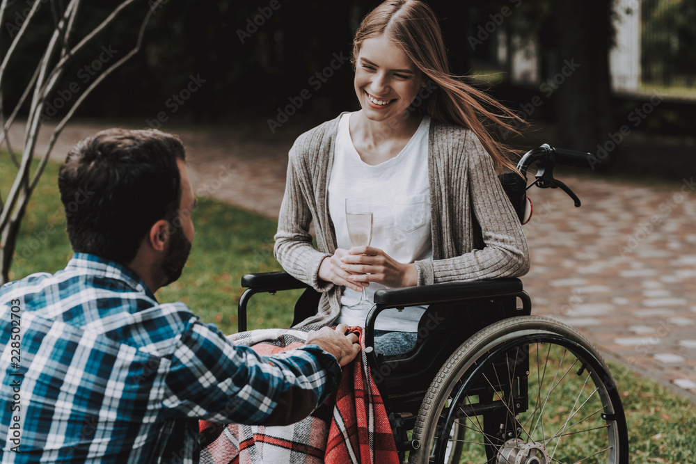 Obraz premium Girl on Wheelchairs with Man on Picnic in Park.