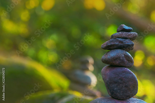 Stacked stone pyramid in front of green blurry background with bokeh