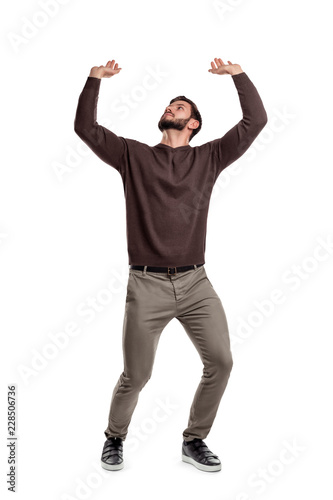 Fototapete A bearded man in casual clothes attempts to hold something heavy from above on a white background