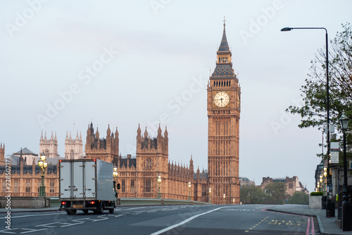A delivery truck crosses Westminster Bridge at dawn in London. Big Ben and the Houses of Parliament. No traffic, no people. Early morning. Covid 19 Coronavirus lockdown