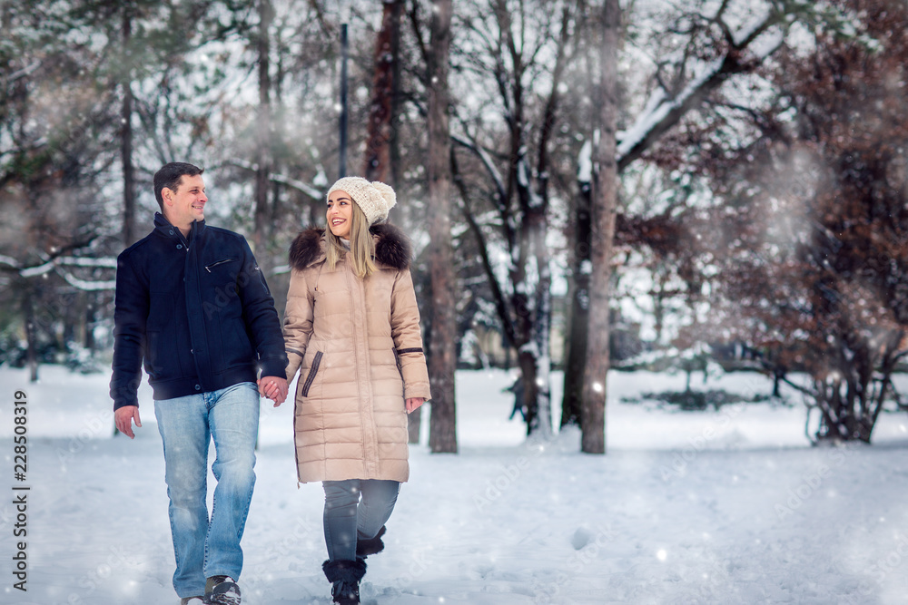 Lovers walking in winter snow- Smiling Couple in Winter Park having fun..