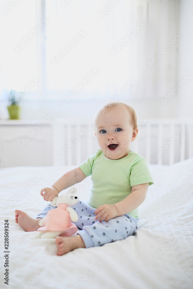 Baby girl sitting on bed and laughing Baby girl sitting on bed and laughing