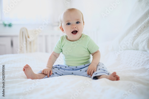 Baby girl sitting on bed and laughing