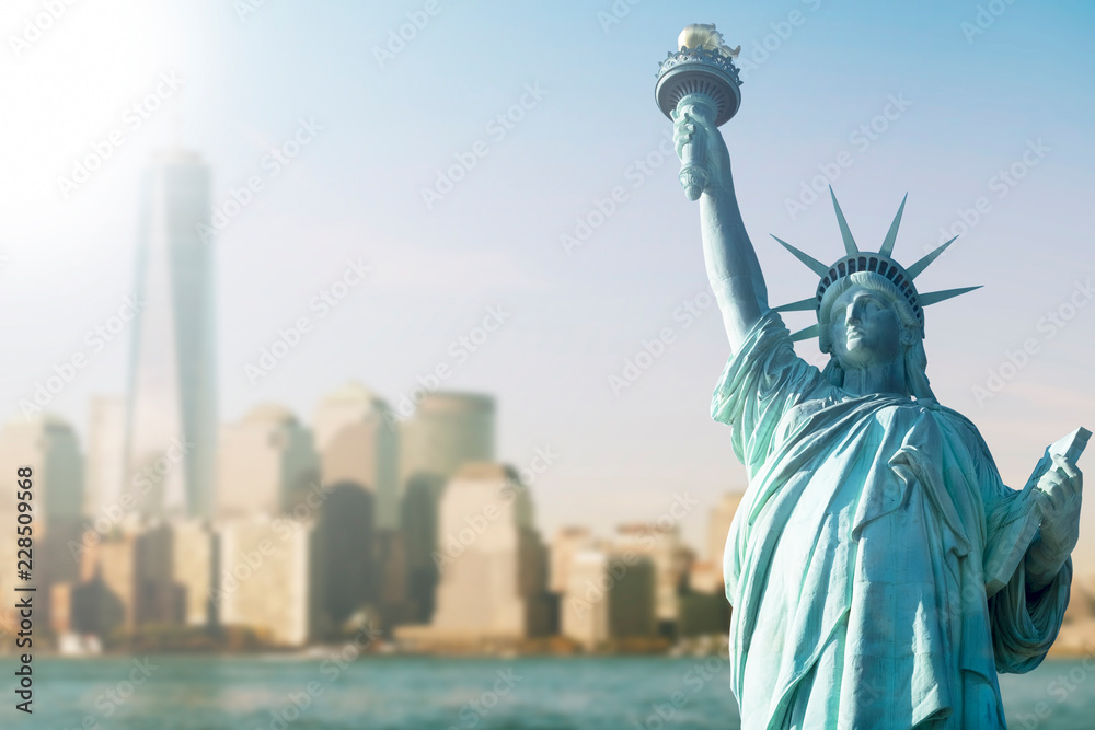 STATUE OF LIBERTY WITH BLUR BACKGROUND OF ONE WORLD TRADE CENTER AND SKYSCRAPERS IN MANHATTAN, NEW YORK, USA