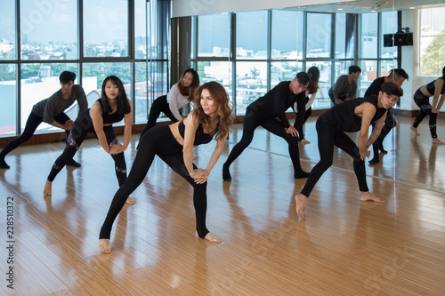 Group of Asian people performing nice contemporary dance during training in light studio