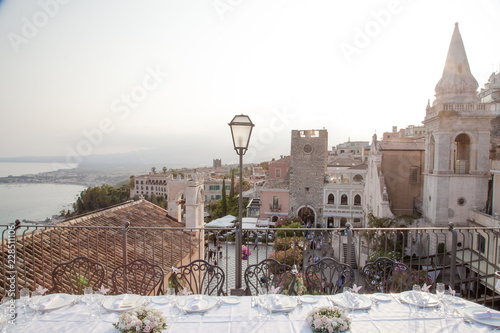 View of sunset over Taormina, Sicily and the mediterranean sea, from roof top terrace, table set for wedding banquet.