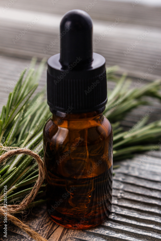 Rosemary essential oil on a gray wooden rustic background Rosemary essential oil on a gray wooden rustic background