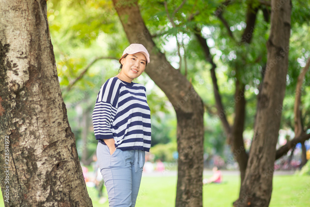 Happy Asian woman smiling and looking at the camera in the park Happy Asian woman smiling and looking at the camera in the park