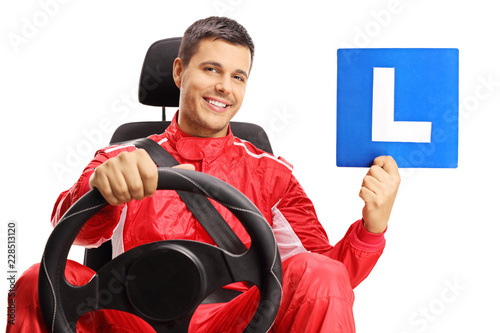 Racer in a car seat holding a learner plate