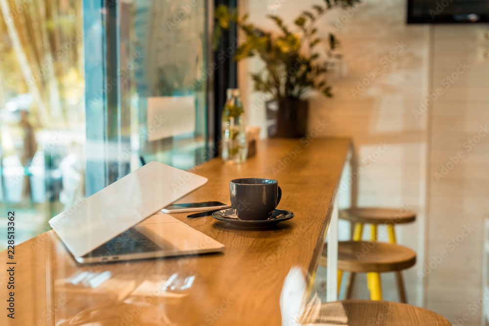 laptop, smartphone, notebook and cup of coffee on wooden cafe counter laptop, smartphone, notebook and cup of coffee on wooden cafe counter