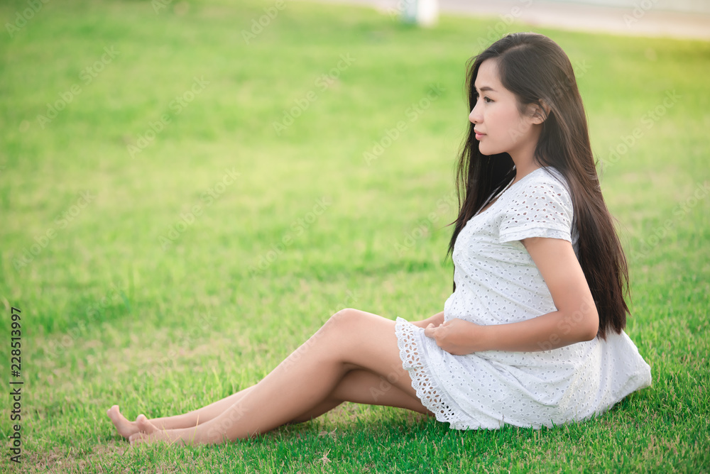 young pregnant woman sitting on the grass young pregnant woman sitting on the grass