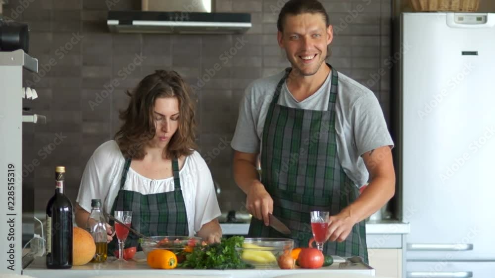 Male and female Cook, couple, husband and wife cook in the kitchen and cut and slice salad and vegetables with a knife Male and female Cook, couple, husband and wife cook in the kitchen and cut and slice salad and vegetables with a knife
