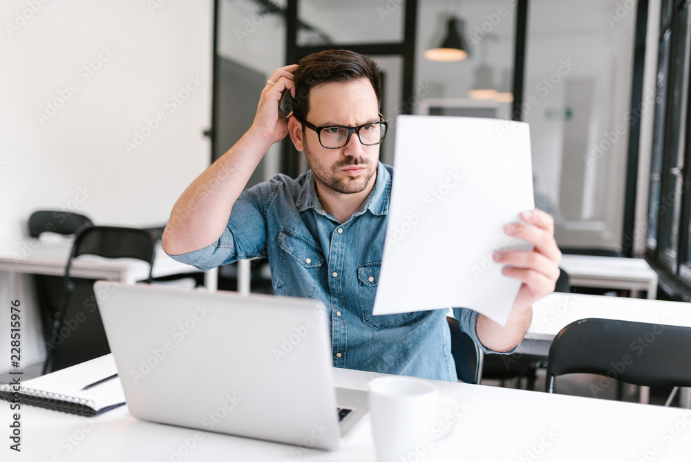 Puzzled young man looking at document. Puzzled young man looking at document.
