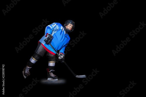 Ice hockey player with stick over black background