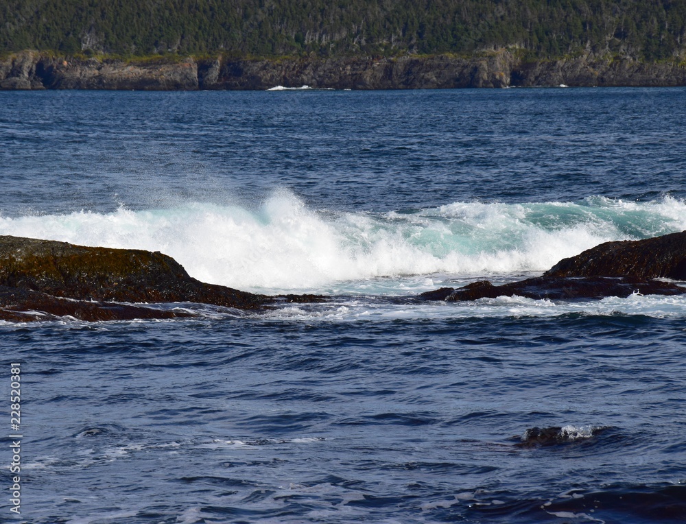 nice rolling wave hitting a rock in the ocean, blue ocean water