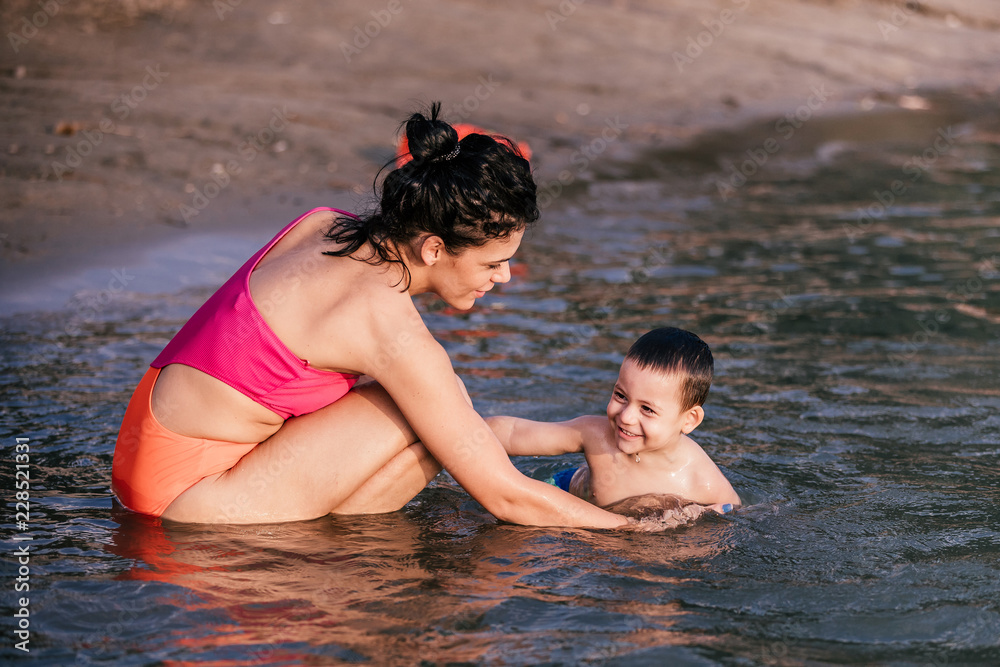 Mother playing with her little son in the water