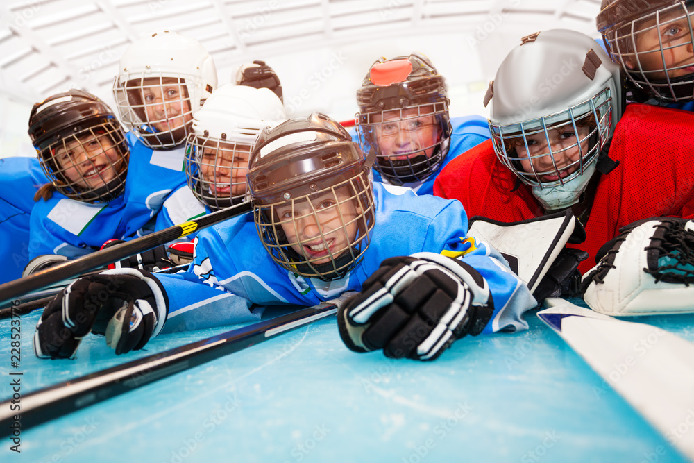 Obraz premium Happy boys in hockey uniform laying on ice rink