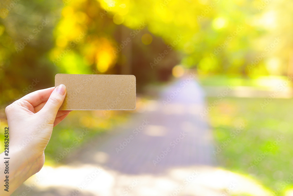 Hand holding empty card in autumn park in sunny rays background. Hand holding empty card in autumn park in sunny rays background.