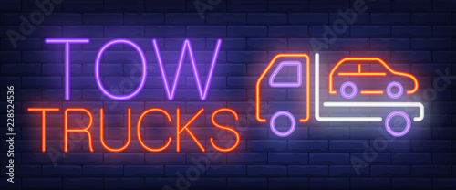 Tow trucks neon text with car being evacuated. Car evacuation advertisement design. Night bright neon sign, colorful billboard, light banner. Vector illustration in neon style.