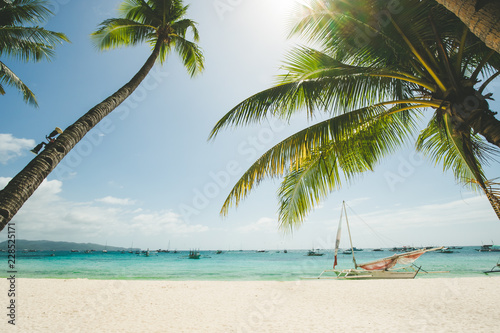 Fototapeta Naklejka Na Ścianę i Meble -  Perfect white sand beach in Boracay, Philippines. Coconut Palm trees against blue sky, boat in ocean. Sunny weather. Travel Background. Nature landscape. Holiday and recreation on exotic island resort