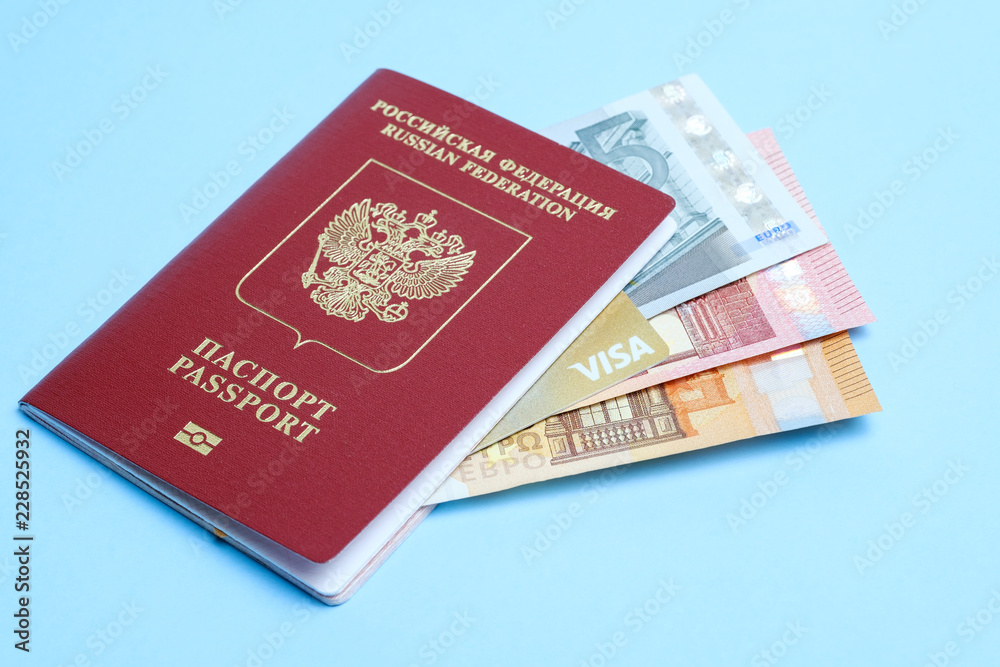 Euro banknotes and VISA card enclosed in a foreign Russian passport isolated on a blue background. Travel to Europe. Euro banknotes and VISA card enclosed in a foreign Russian passport isolated on a blue background. Travel to Europe.