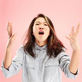 Screaming, hate, rage. Crying emotional angry woman screaming on pink studio background. Emotional, young face. Female half-length portrait. Human emotions, facial expression concept. Trendy colors