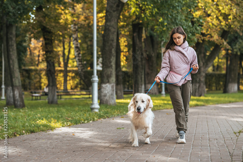 young woman walking with guide dog in park