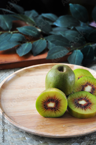 Fresh Red KIwifruit on Plate with Green Leaves on Background