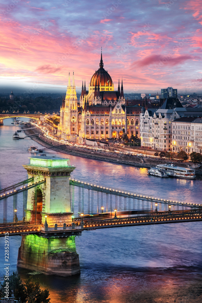 Aerial view of the Parliament building at sunset in Budapest, Hungary. Green light on the Chain Bridge pillar