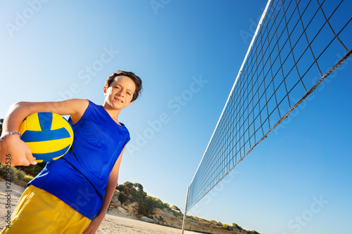 Young volleyball player with ball next to the net