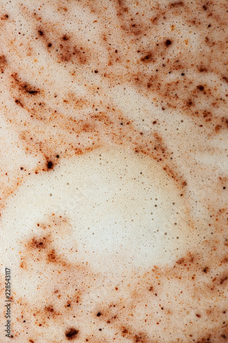 Macro image of milky coffee bubbles sprinked with chocolate, vertical image