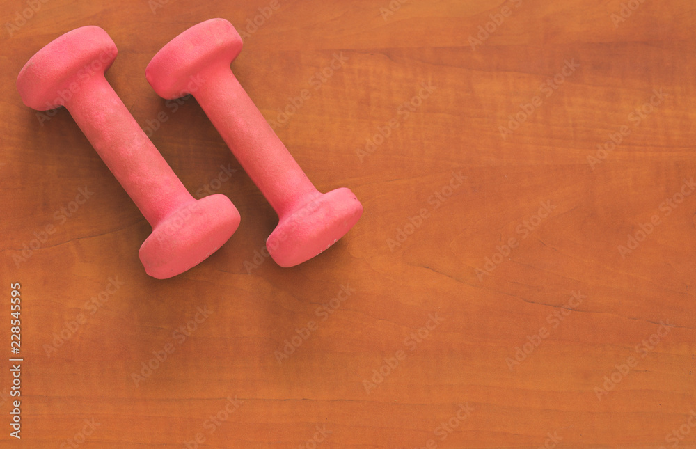 Pair of pink dumbbells on wooden background. Pair of pink dumbbells on wooden background.