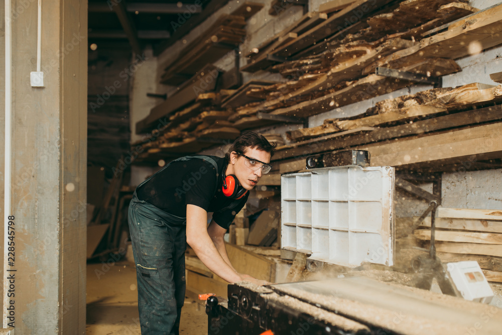 Young master carpenter working in his woodwork or workshop.