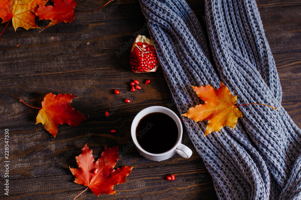 Coffee mug with autumn maple leaves and women's woolen scarf on a wooden table Coffee mug with autumn maple leaves and women's woolen scarf on a wooden table