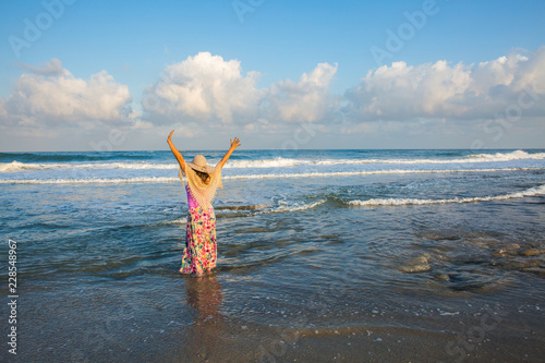 Woman with big hat standing on the beach